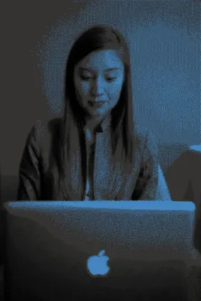 A female executive sits looking at the screen of her Apple laptop.